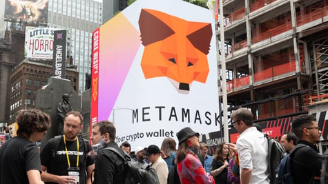 People stand by a MetaMask billboard in Times Square in New York City.