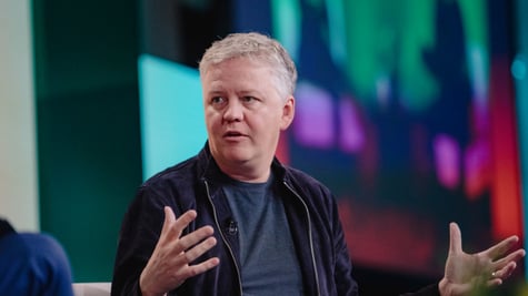 Cloudflare CEO Matthew Prince black suit, grey shirt, no collar, white hair, head turned left