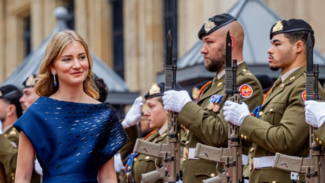 Princess Elisabeth of Belgium, blond hair, two army men in uniform, black guns, blue dress