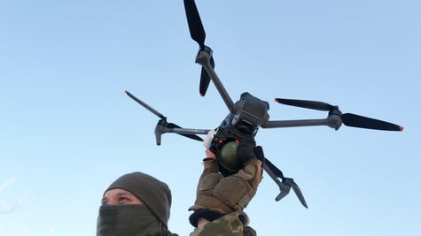 man in ukraine military uniform, facial mask, drone in hand, had in the blue sky, black
