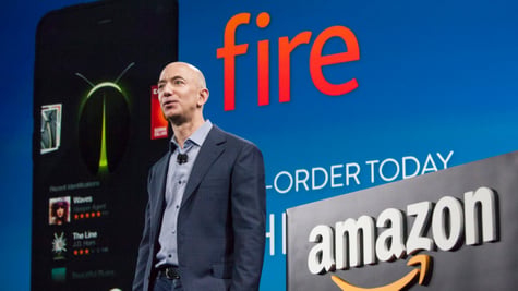 young Jeff Bezos, bald man in blue shirt and grey suit, amazon logo, fire sign in orange