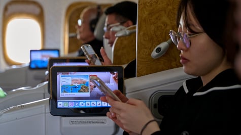 asian woman looks at her phone, black hair, tiny television screen, more passengers in the back