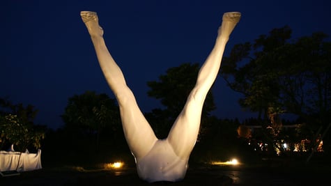 white spread legs in the dark blue night sky, warm lit sculpture