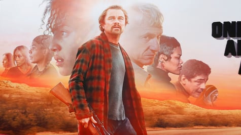 leonardo di caprio in red and white flannel shirt, shotgun, sunset, orange field, road