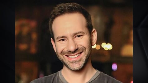 OnlyFans owner Leonid Radvinsky in grey shirt, smilind, black short beard, dark eyes, white teeth