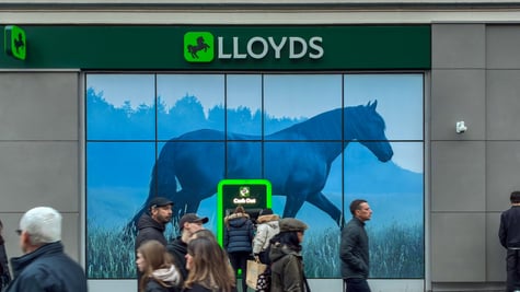 lloyds bank, green logo, people passing by, black horse logo, grey wall, warm people's outfits
