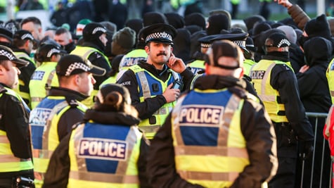 Police officers in yellow reflective rests, black hats with white squares, blue police signs