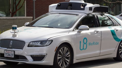 silver car with baby blue weRide logo on left door