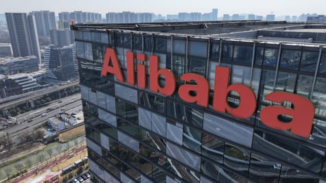 alibaba orange logo on top of dark glass building