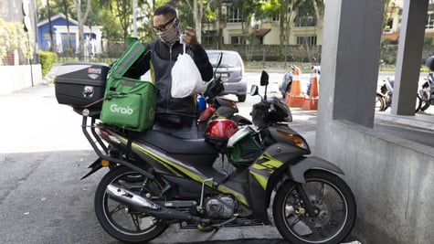 delivery driver on moped, white plastic bag, green delivery box, white GrabFood logo