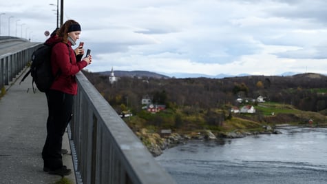 people on bridge, red jacket, maelstrom , flooded river, blue sky, white clouds, smartphone 