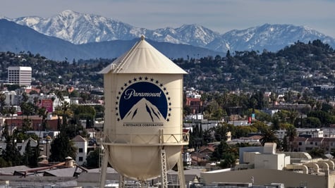 ivory water tower, blue paramount logo on it, mountains in the background, 