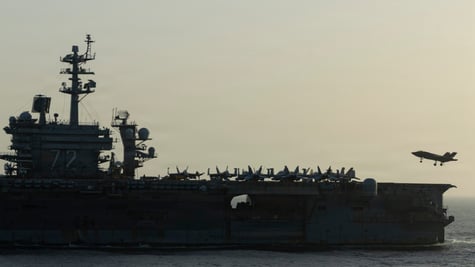 USS Abraham Lincoln (CVN 72) war ship at sea during sunset, plane in sky, plane fleet onboard,
