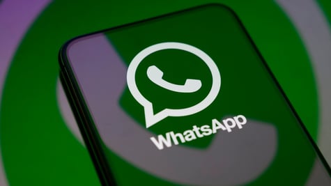 WhatsApp logo reflection on a smartphone's screen, green, white