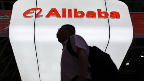 Man walks past Alibaba logo