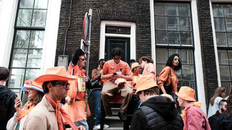 people dressed in orange, amsterdam streets, man on phone, sits on stairs, big windows