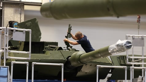 white man, machine gun, leopard 2A7 battle tank, indoors, blonde man