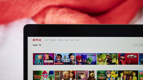 black laptop frame, white screen, netflix kids section, animated faces, red blanket