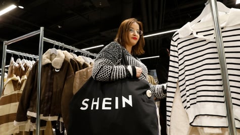 young woman, black shopping back, white shein sign, winter coat with white fur, black stripes
