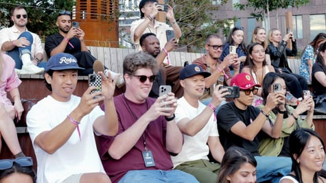about thirty white people raising their smartphones to film, t-shirts, hats, 