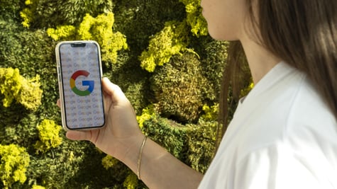 Google logo on white smartphone screen, white t-shirt, white female, long dark brown hair, green