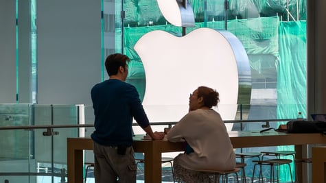 huge silver apple logo, asian man standing ,fat asian woman sitting, green background
