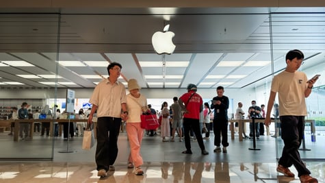 middle aged white asian couple exit apple store, logo, pink pants, black hair, glass wall, white tshirt