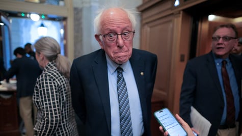 bernie sanders, white hair, band forehead, telephone, light blue shirt, glasses