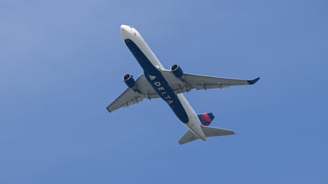delta airline white plane in blue sky, delta sign on bottom on the plane