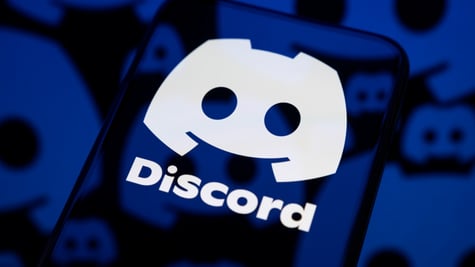 dark smartphone screen reflects one big white discord logo, little darker ones are in the back