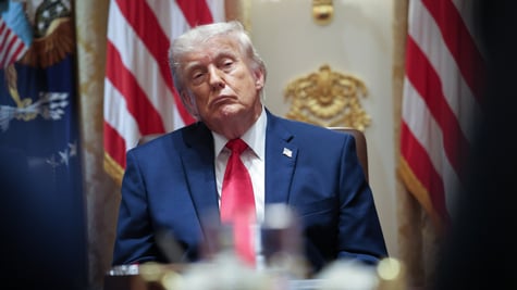 donald trump, two US flags, one flag pin in dark blue suit, white collar shirt, red tie, blonde hair