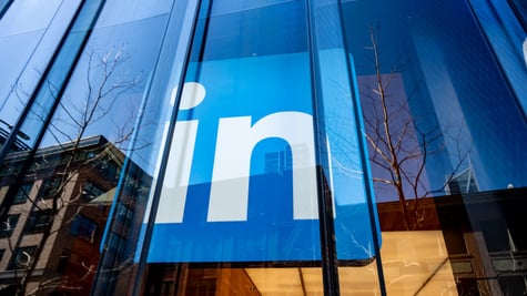 LinkedIn logo behind glass wall of a huge building, reflection of the cityscape