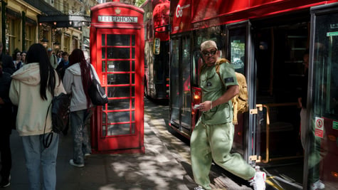 london, black man in light green throusers and shirt, red telephone booth