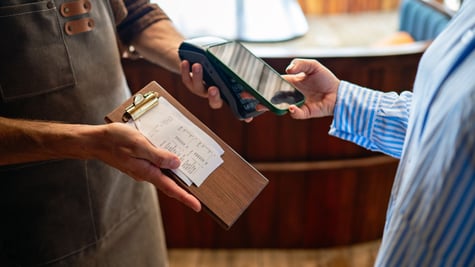 Person paying the bill by card while server holds the card reader