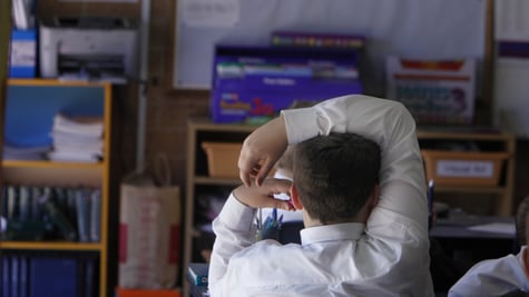 white male school boy in classroom, white collar shirt, right hand over head, light hair