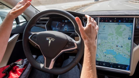 white man hands, black tesla wheel, screen with map on it, car front window, bright red shirt