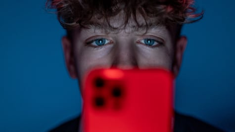 teen boy, curly hair, red smartphone, dark blue room, blue eyes
