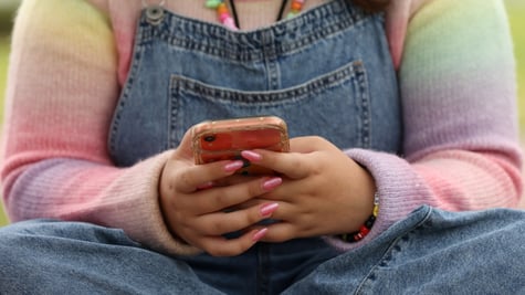 pink nails, smartphone, jeans, rainbow color top