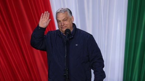 victor orban waves right hand, hungarian flag color curtain, red, white, green, black jacket, grey hair