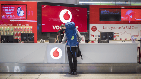 vodafone red kiosk, traveler in huge light blue backpack,, 