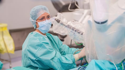 female doctor, light blue face mask and hair net, light mint scrubs, glasses, operating room, 