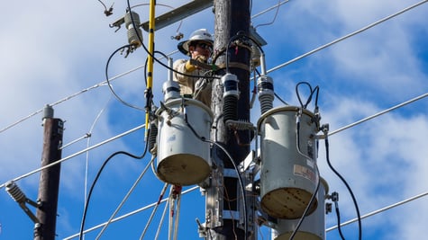 electricity wires, blue sky, wwhite cloud, man in helmet fixing transformer