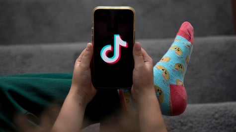 A child holds a smartphone displaying the TikTok logo in an arranged photograph in Sydney, Australia