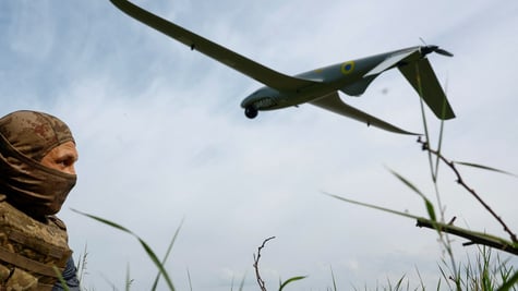 white soldier in field with tall grass, blue sky, white clouds, huge military drone in the sky