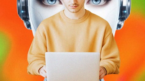 A person sitting at their laptop, big robot's head behind it
