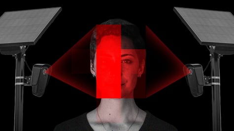 A woman's face lit up by two surveillance cameras