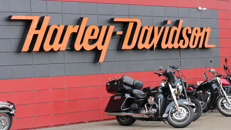 Harley-Davidson sign on side on brick building with two motorcycles in front of it