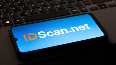 IDScan.net logo is on a smartphone screen, black keyboard in the back,