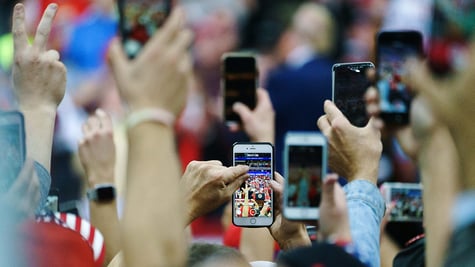 Attendees hold up their smartphones to take videos during a rally with U.S. President Donald Trump in Minneapolis