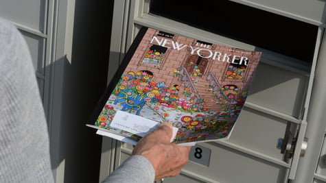 Person holding New Yorker magazine near mailbox